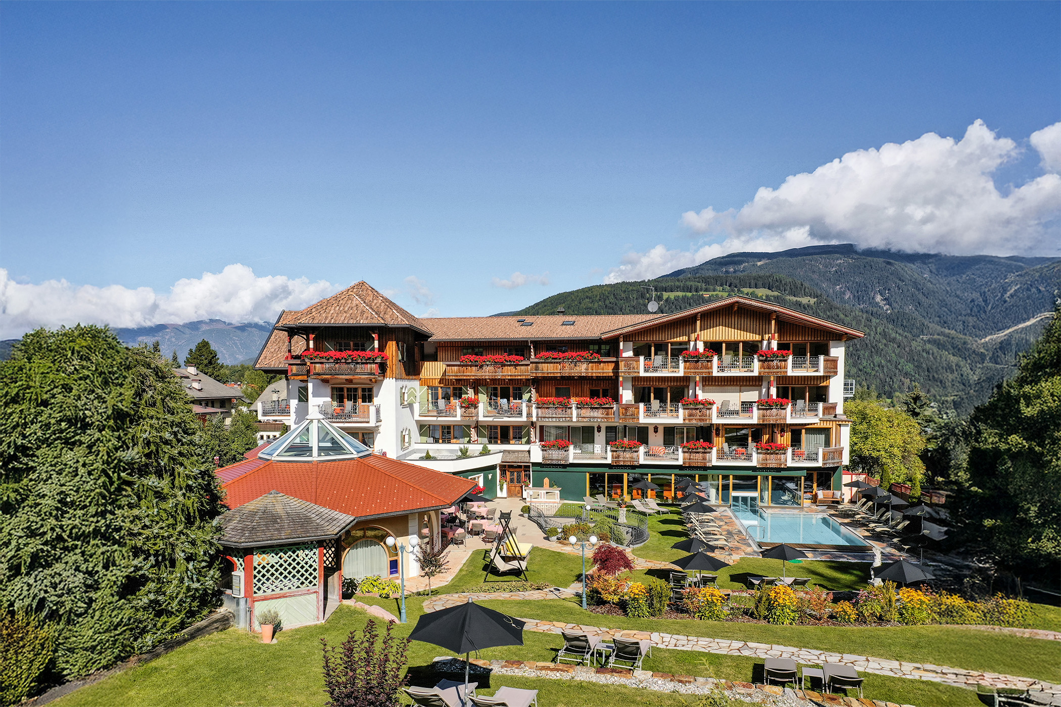 Große Bergferienanlage mit Balkonen, einem Swimmingpool und gepflegten Gärten. - Mirabell Dolomites Hotel