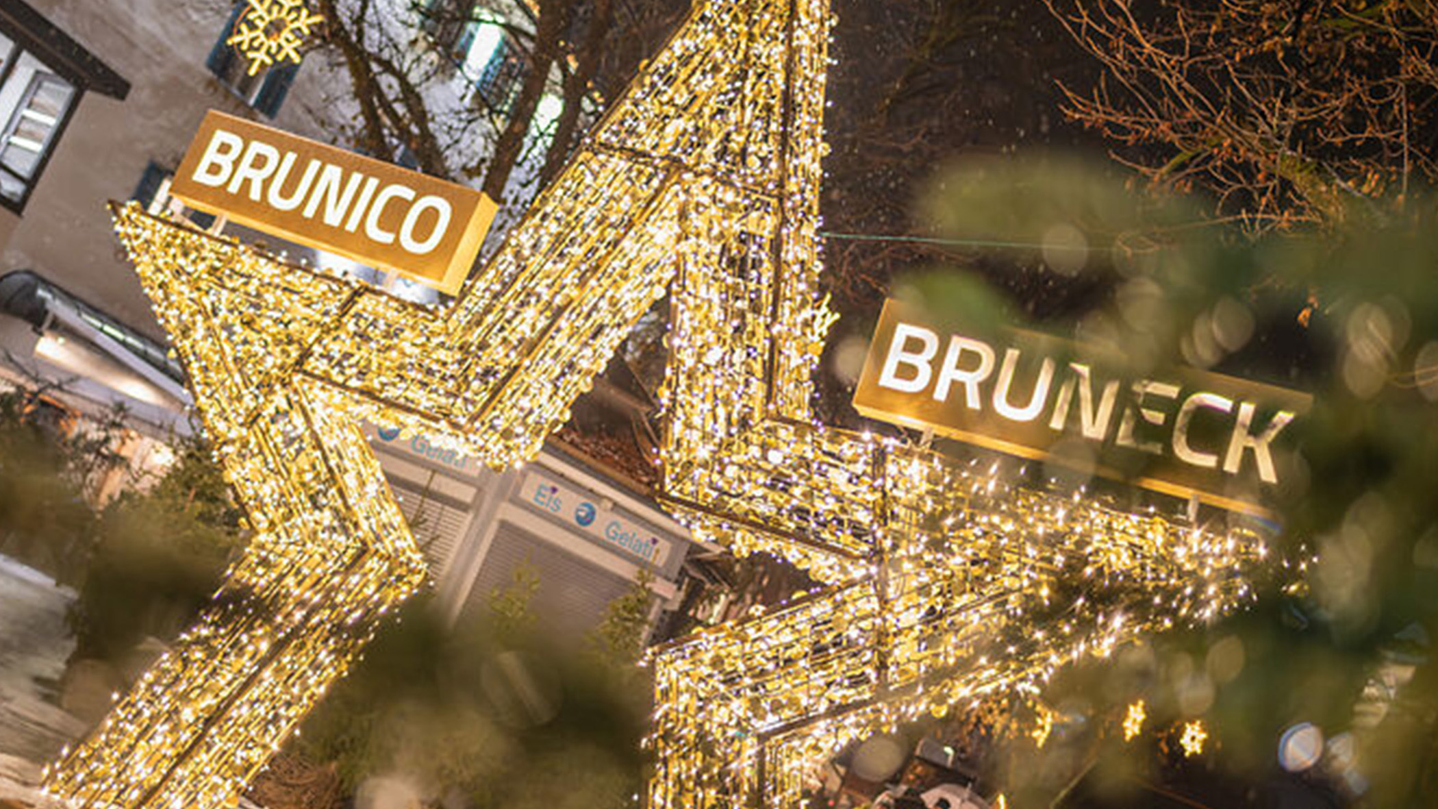 Große, beleuchtete Sterndekorationen mit den Aufschriften „Brunico“ und „Bruneck“ bei einer festlichen Veranstaltung im Freien. - Mirabell Dolomites Hotel